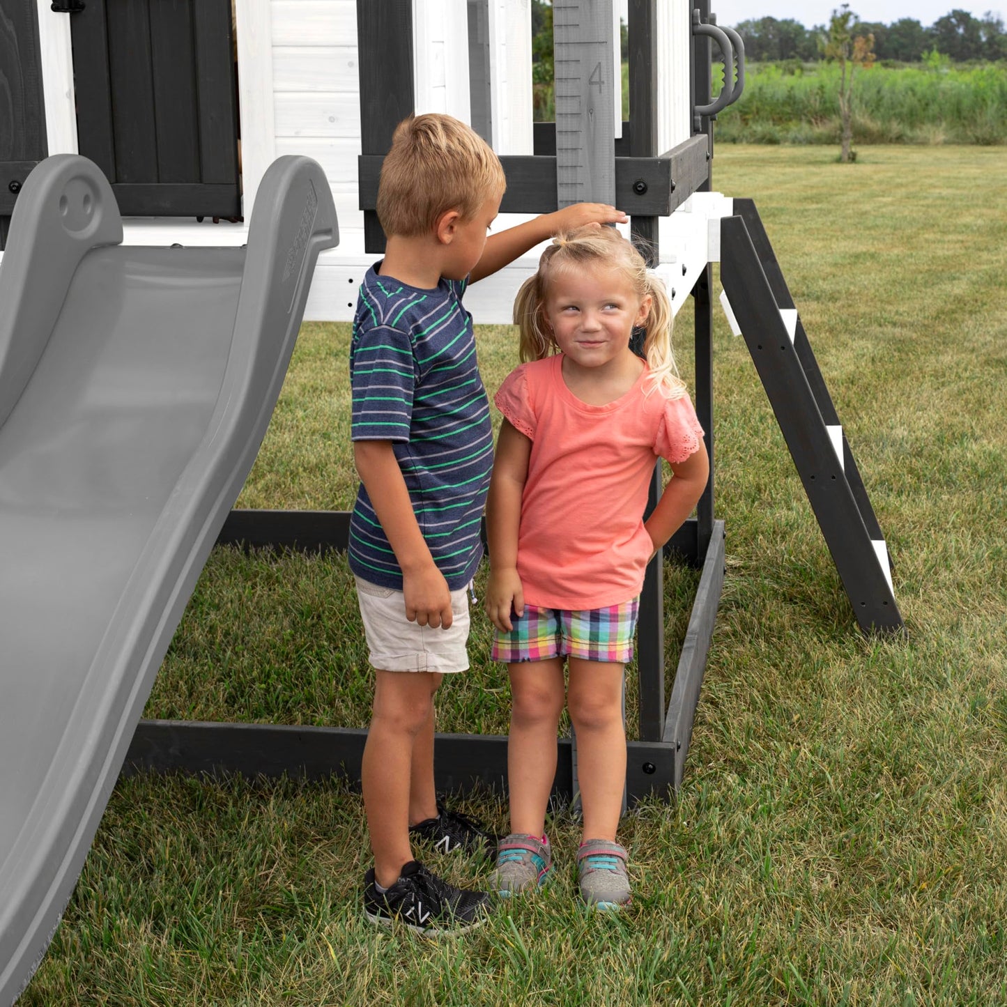 Backyard Discovery Sweetwater Heights White Elevated Cedar Wooden Kids Playhouse with Wave Slide, Play Kitchen, Step Ladder, Half Door, Wrap-Around Deck, Windows, Bell, Growth Chart for Outdoor Play